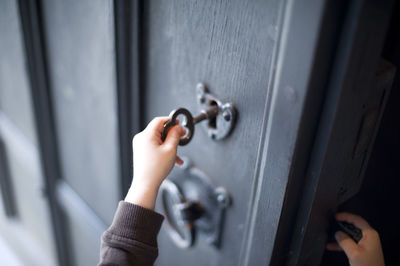 Cropped hand of child unlocking door at home