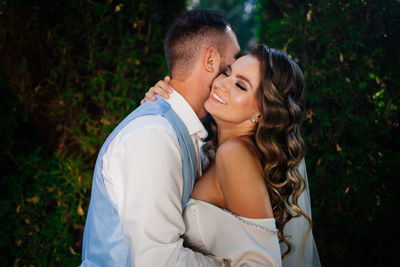 Newlywed couple embracing while standing outdoors