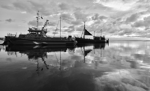 View of fishing boats at harbor against sky