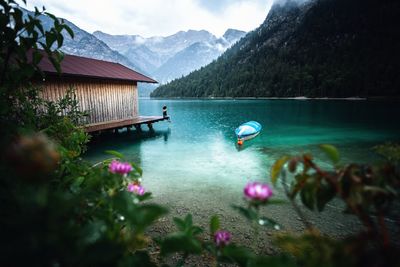 Young woman sitting over wooden boathouse on the alpine lake. majestic nature background.	