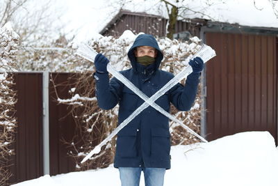 Portrait of man holding icicles during winter
