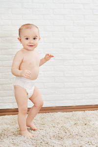 Portrait of cute baby boy standing against wall