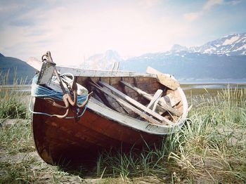 Abandoned boat moored on shore against sky