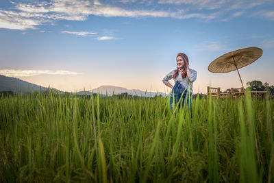 Woman standing on grassy field against sky