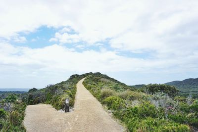 Rear view of walkway amidst mountains against sky