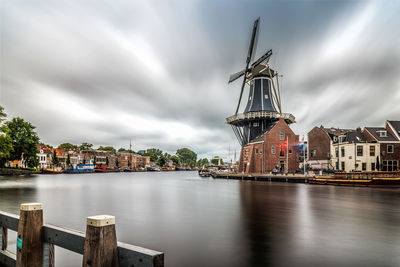 Commercial dock by river against cloudy sky