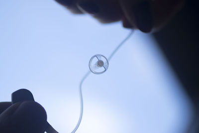 Close-up of hand holding eyeglasses against blue sky