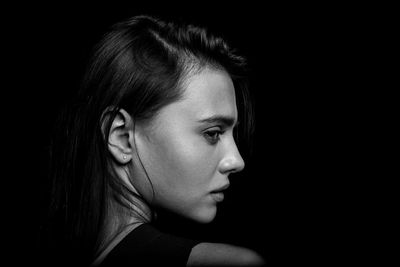 Close-up of young woman against black background