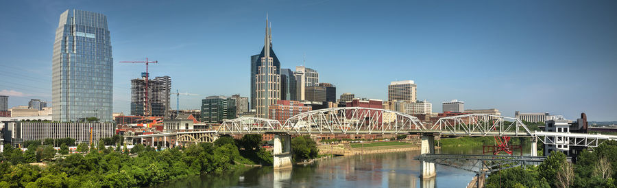 Bridge over river by buildings against sky in city