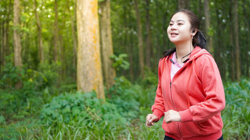 Smiling young woman standing in forest