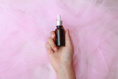 Close-up of hand holding pink bottle