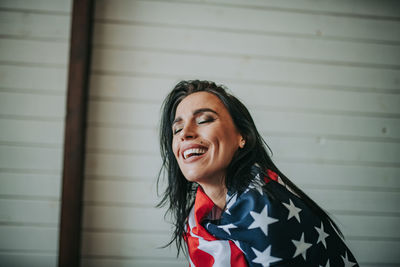 Woman with american flag against wall