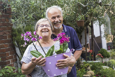 Cheerful couple with flowers in basket at yard