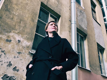 Low angle view of young woman standing against building