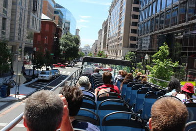 Rear view of people sitting on tour bus in city