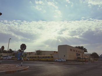 Cars on road against cloudy sky on sunny day