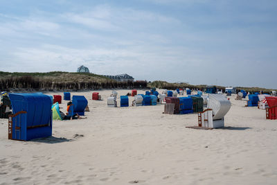 Hooded chairs on beach against sky