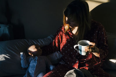 Woman sitting with baby on bed at home