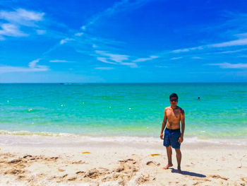 Full length of shirtless man standing on beach