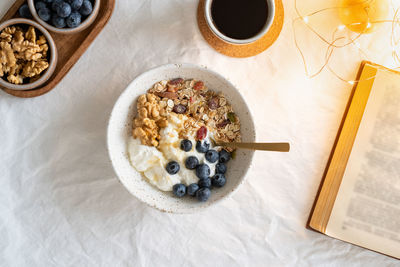 Top view book and christmas healthy lifestyle breakfast with granola muesli and yogurt in bowl 