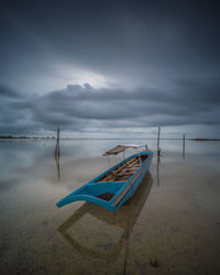 Fishing boat moored on beach against sky