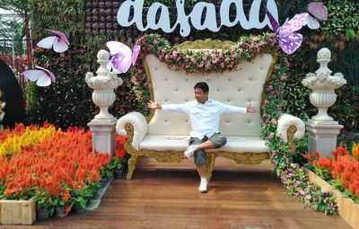 Full length of man sitting by flowers