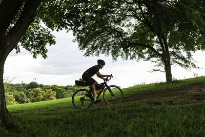 Full length of man riding bicycle on grassy land