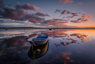 Boats moored in lake against sky during sunset