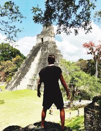 Rear view of man with arms raised against sky