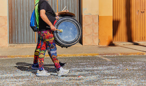 Popular festivals man playing bass drum in multicolored suit. popular festivities