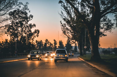 Cars on road against sky during sunset