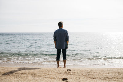 Man standing against sea at beach during sunny day