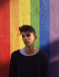 Handsome man standing against rainbow wall