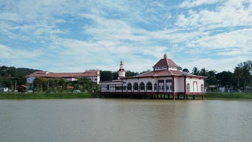 Building by river against cloudy sky