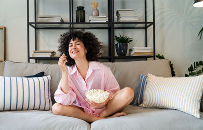 Portrait of young woman sitting on sofa at home