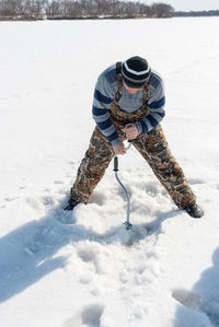 Mid adult man subglacial fishing in frozen lake