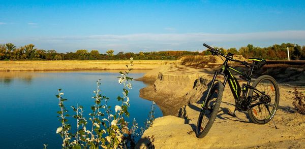 Bicycle by lake against sky