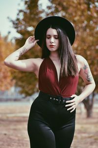 Beautiful young woman in hat standing on land