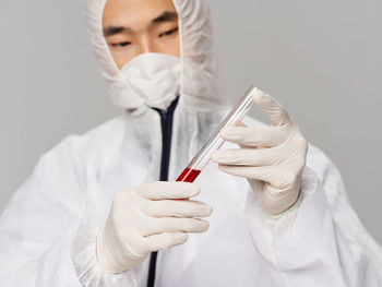 Doctor holding tube filled with blood against white background