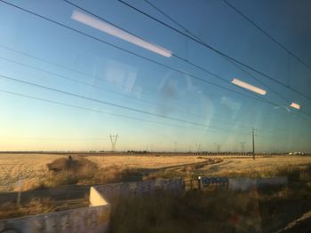 Electricity pylon on field against sky at sunset