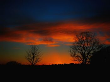 Silhouette trees against dramatic sky during sunset