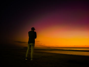 Silhouette man standing on beach against sky during sunset