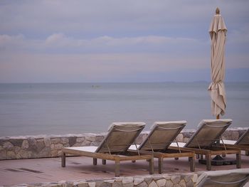 Rear view of sun loungers against calm sea