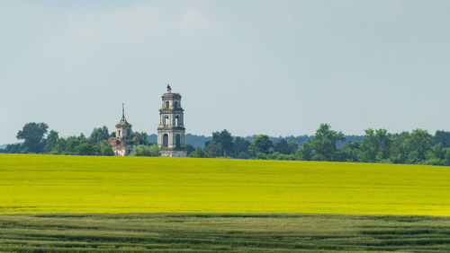 Scenic view of field by building against sky