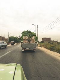 Cars on road against sky in city