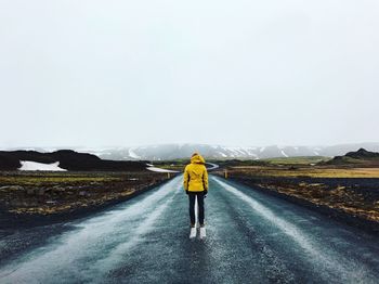 Rear view of man standing on road against sky