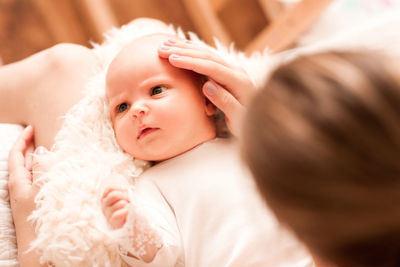 Close-up of cute baby girl lying on bed at home