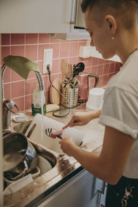 Woman in kitchen washing dishes