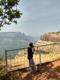 Rear view of man looking at mountains against sky