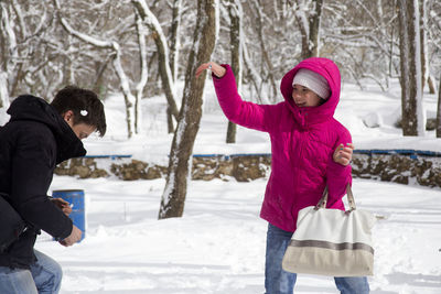 Rear view of mother with daughter standing on field during winter